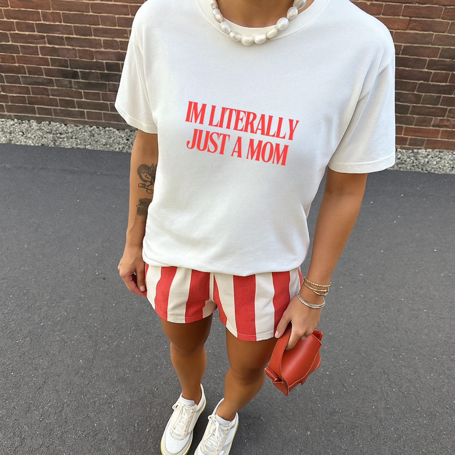 Person wearing a white t-shirt with red text and red and white striped shorts, standing against a brick wall.