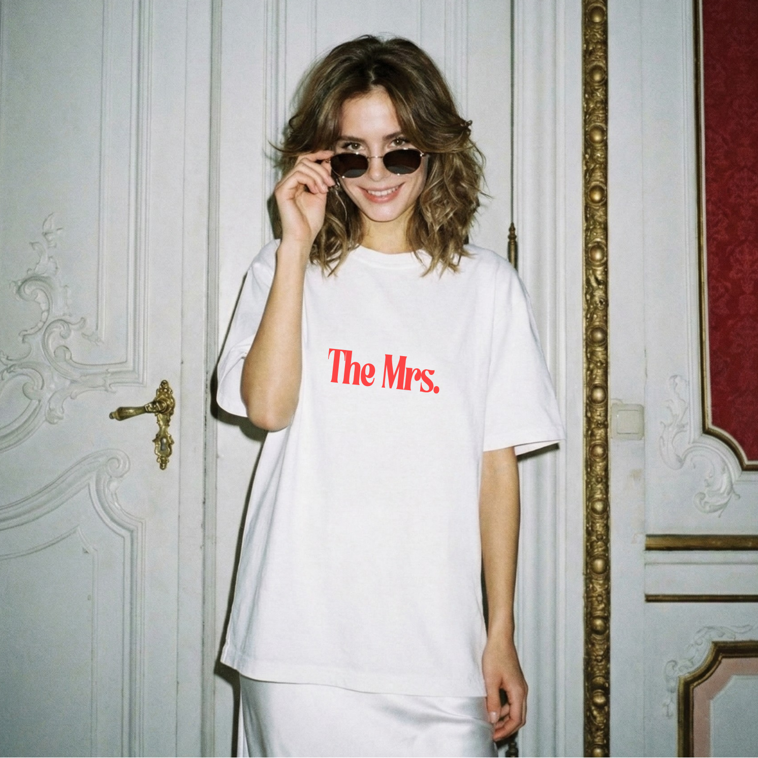 Woman wearing a white t-shirt with 'The Mrs.' text in a decorative interior setting